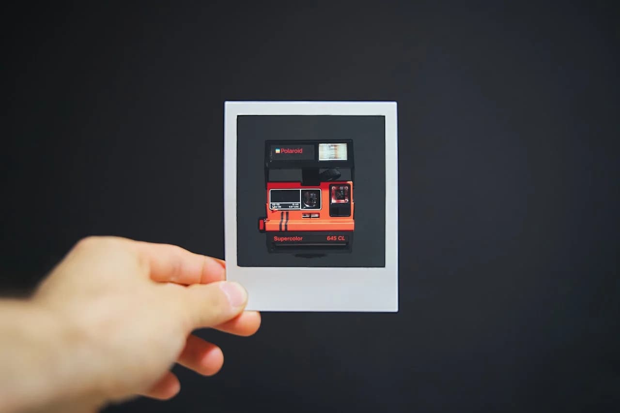 Dłoń trzymająca mniejsze zdjęcie aparatu Polaroid