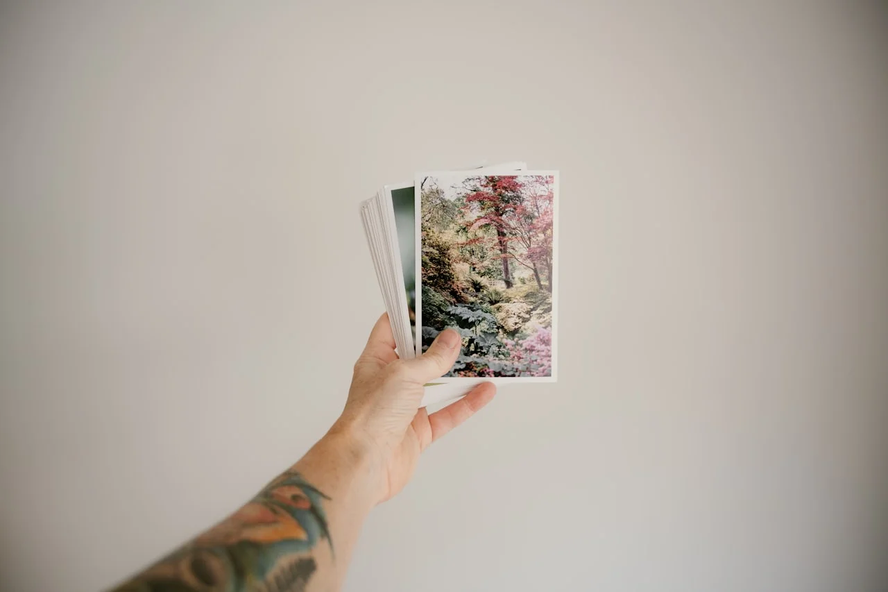 Ręce przeglądają album pełen wydrukowanych zdjęć w formacie 10 × 15 cm