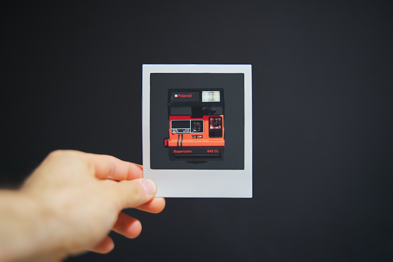 Dłoń trzymająca mniejsze zdjęcie aparatu Polaroid