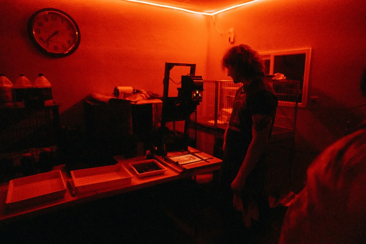 Fotograf w ciemni pod czerwonym światłem podczas obróbki zdjęcia