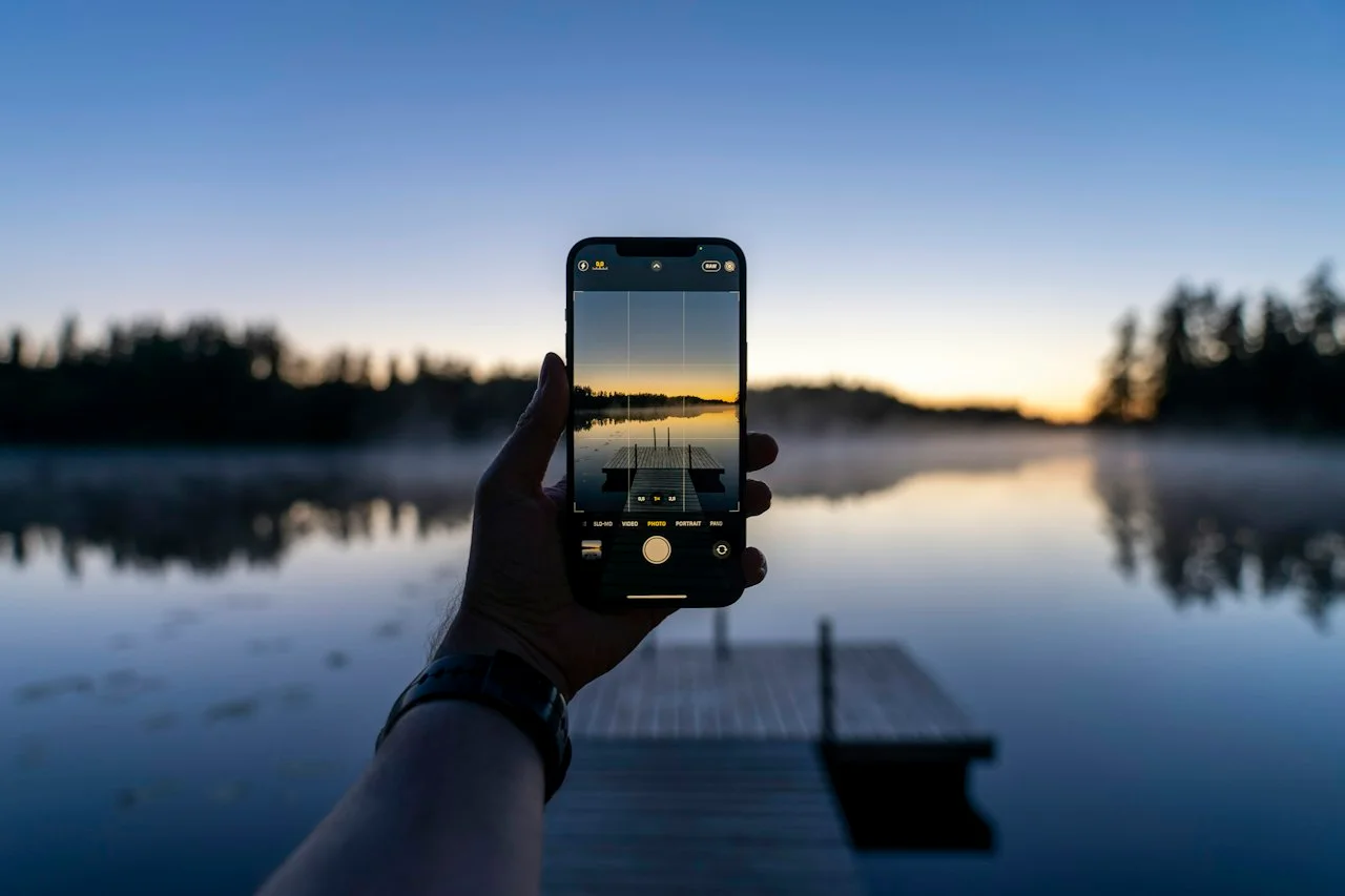 Telefon z siatką kadrowania w aplikacji aparatu na tle jeziora o zmierzchu