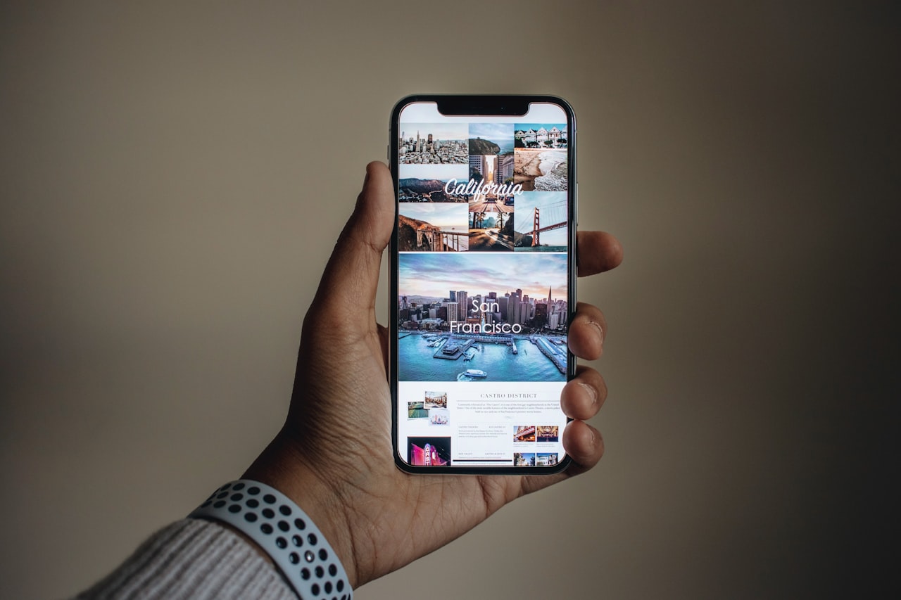 Dłoń trzymająca smartfon nad biurkiem ze zdjęciami